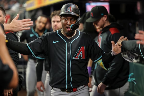 Arizona Diamondbacks' Geraldo Perdomo high-fives teammates in the dugout after scoring a run in the third inning of a baseball game against the Atlanta Braves, Wednesday, June 4, 2025, in Atlanta. (AP Photo/Colin Hubbard)