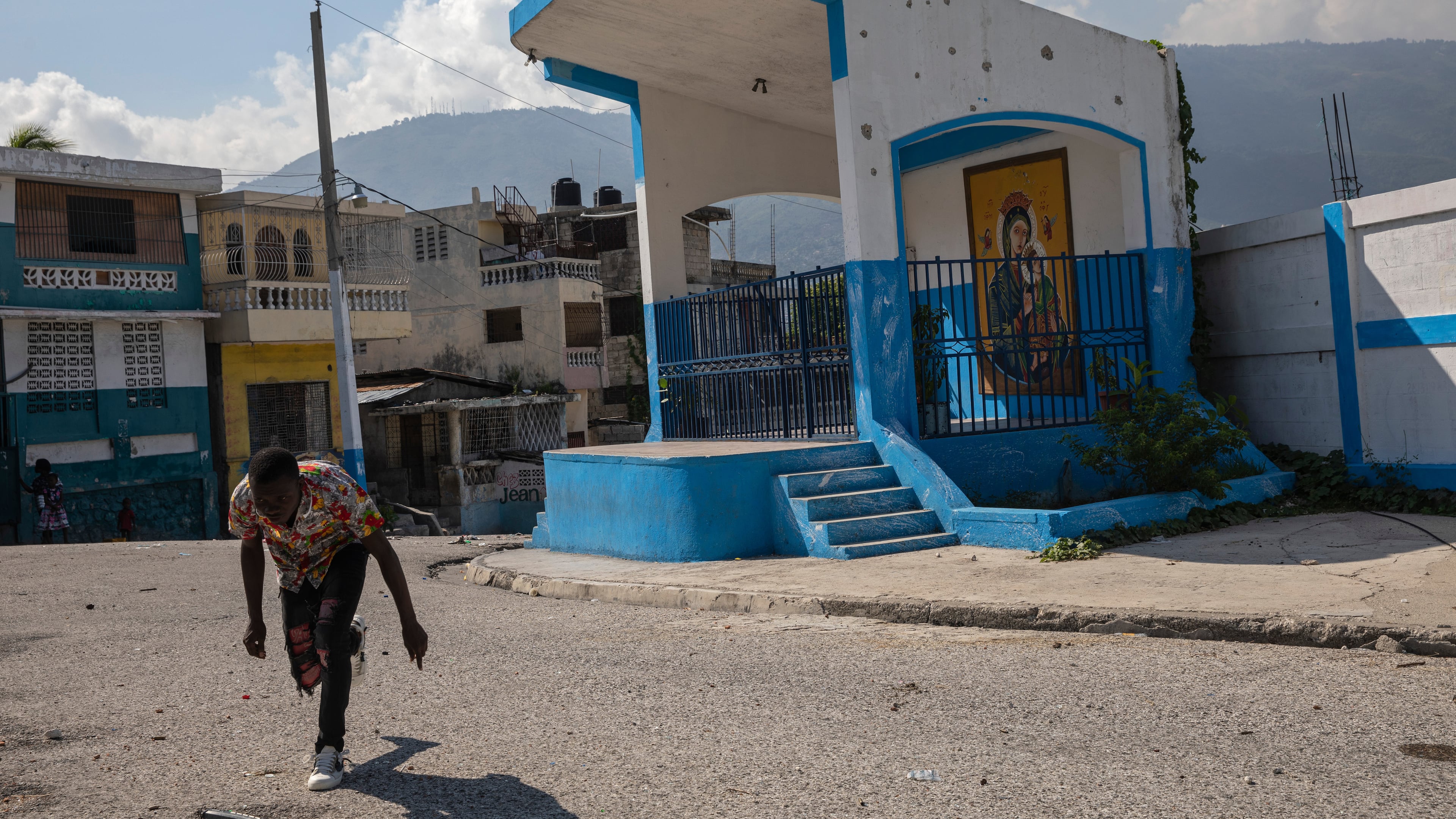 FILE - A man runs for cover as he crosses a barricaded street in the gang-controlled Bel Air neighborhood of Port-au-Prince, Haiti, Sept. 25, 2021. (AP Photo/Rodrigo Abd, File)
