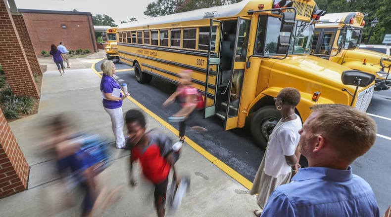 Dr. Derek Schroll (right) watches students arrive for their first day of school at Coleman Middle School at 3057 Main Street in Duluth. In the middle school with nearly 800 students, teachers and students were already preparing to work on their first large-scale projects of the year using different forms of technology such as computer data analysis and 3D printers. JOHN SPINK/JSPINK@AJC.COM