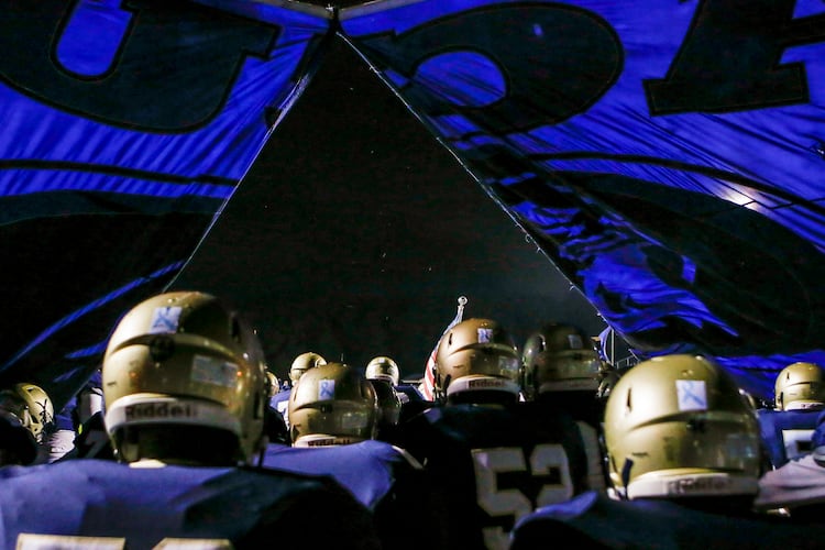 The Dacula football team breaks through its banner before running onto the field for a game in Dacula. The team was given only a 41.3% chance of reaching the GHSA football playoffs. (Casey Sykes for the AJC)