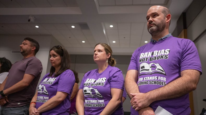 At a Cobb school board meeting in July, demonstrators wore shirts calling for the district to "ban bias, not books" after a teacher was removed from her classroom for reading a book that challenges gender norms to fifth graders. At the board's most recent meeting in April, Superintendent Chris Ragsdale announced that four more books are being removed from school libraries for containing inappropriate content. (Katelyn Myrick / AJC file photo)