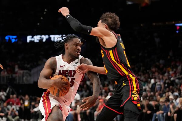Miami Heat guard Davion Mitchell (45) dribbles against Atlanta Hawks forward Jalen Johnson (1) in overtime of an NBA play-in tournament basketball game against the Friday, April 18, 2025, in Atlanta. (AP Photo/Brynn Anderson)