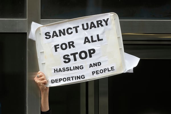 A person holds up a sign during a news conference and rally by immigrant justice organizations and advocates protesting ICE arrests in San Francisco, Wednesday, May 28, 2025. (AP Photo/Jeff Chiu)