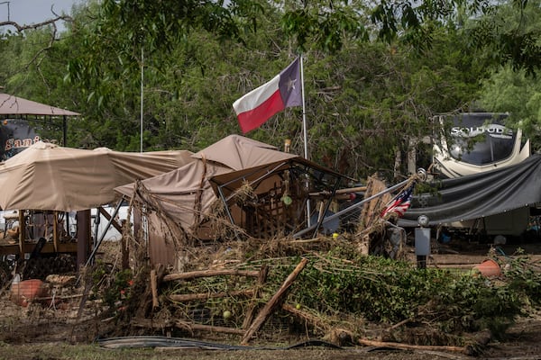 A Texas flag waves in the wind amongst debris from flash flooding at Cedar Stays RV Park in Marble Falls, Texas, Monday, July 7, 2025. (Mikala Compton /Austin American-Statesman via AP)