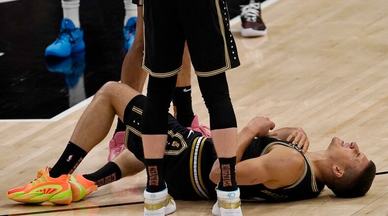 Atlanta Hawks guard Bogdan Bogdanovic (13) lies on the court after an injury during the first half of Game 6 of an NBA basketball Eastern Conference semifinal series against the Philadelphia 76ers, Friday, June 18, 2021, in Atlanta. Bogdanovic stayed in the game. (AP Photo/John Bazemore)