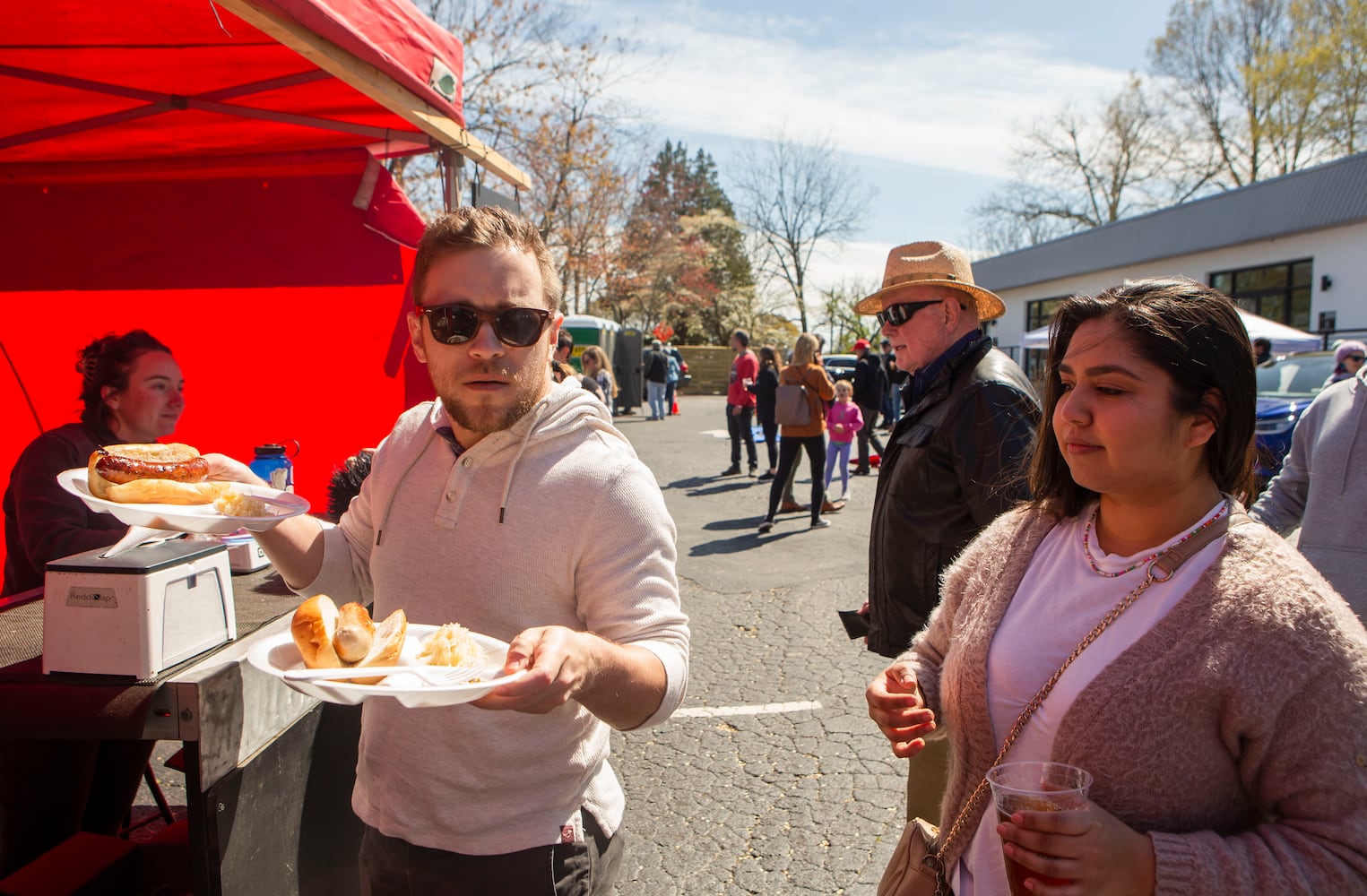 Sam Madert (left) and Gisella Rodriguez (right) order bratwursts during Goethe Fruhlingsfest on Saturday, March 18, 2023, in Avondale Estates. CHRISTINA MATACOTTA FOR THE ATLANTA JOURNAL-CONSTITUTION. 