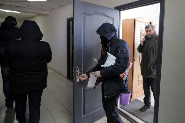 FILE - Police carry documents and computers from the office of the Belarusian Association of Journalists as Andrei Bastunets, the head the association, right, looks on in Minsk, Belarus, on Feb. 16, 2021. (AP Photo, File)