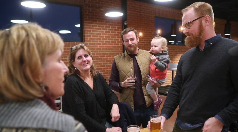 Furloughed workers Daria Labinsky (from left), Maureen Hill, Chip Daymude with his daughter Penny, 18-months, and Nathan Jordan discuss the shutdown at Sweetwater Brewing Company during an event offering free food and beer to furloughed federal workers on Thursday, Jan. 10, 2019, in Atlanta.