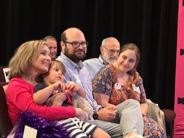 Lois Reitzes listens to tributes at her going away party at WABE with her family, (from left) grandson Max in her lap, son Michael, daughter Jackie and husband Don. (Rodney Ho/AJC)