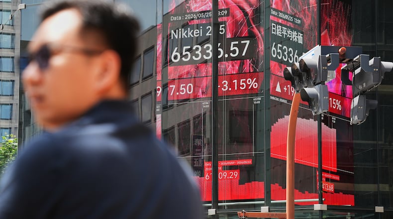 A person stands in front of an electronic stock board showing Japan's Nikkei index, seen through the glass wall of an office building Monday, May 25, 2026, in Tokyo. (AP Photo/Eugene Hoshiko)