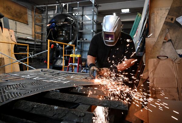 Smith puts the finishing touches on his sculpture, "The Burning Book," which is expected to go up in flames as participants toss logs into the sculpture’s built-in furnace, at the annual Burning Man festival. (Hyosub Shin/AJC)
