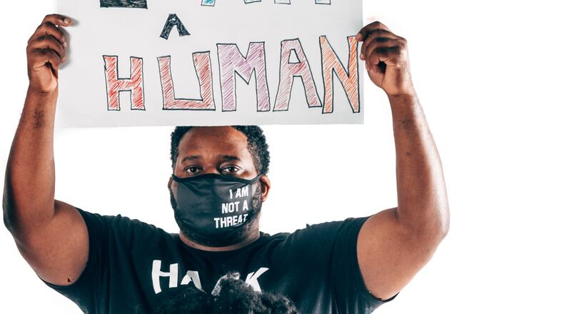 Khalil Thompson of Atlanta raises a sign reminding some that he is not a threat. He is human.