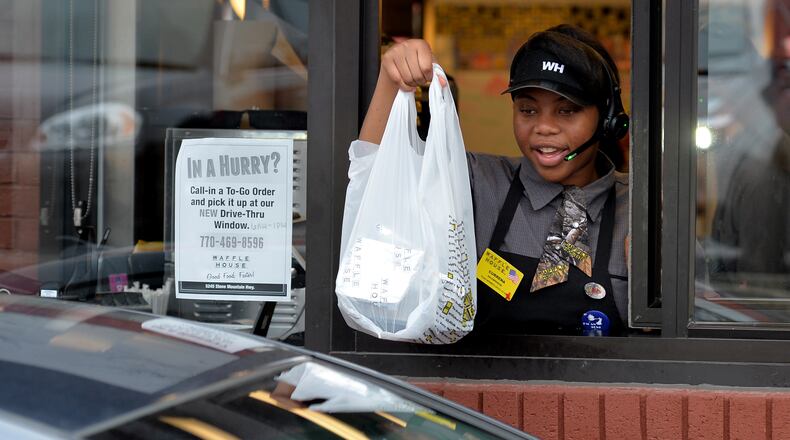 Currena Curry hands a customer their food at the Waffle House drive-thru window in Stone Mountain. It’s the only Waffle House in the 1,800-restaurant chain to have a drive thru. BRANT SANDERLIN/BSANDERLIN@AJC.COM