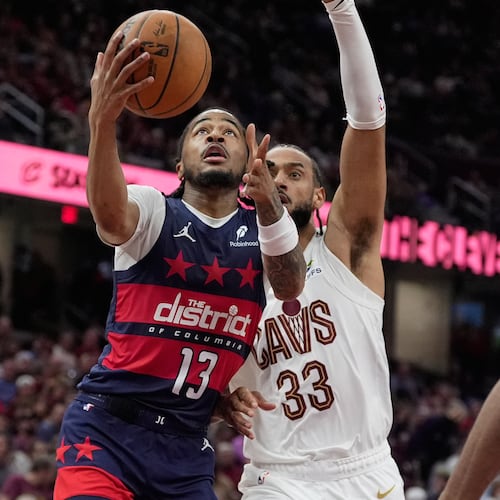Washington Wizards guard Sharife Cooper (13) goes to the basket past Cleveland Cavaliers forward Olivier Sarr (33) in the second half of an NBA basketball game in Cleveland, Sunday, April 12, 2026. (AP Photo/Sue Ogrocki)