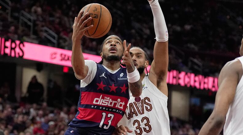 Washington Wizards guard Sharife Cooper (13) goes to the basket past Cleveland Cavaliers forward Olivier Sarr (33) in the second half of an NBA basketball game in Cleveland, Sunday, April 12, 2026. (AP Photo/Sue Ogrocki)
