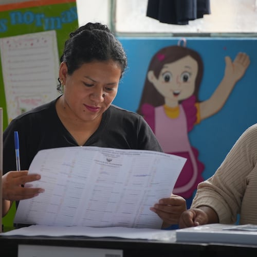 An election official checks voter lists as voting resumes at polling stations affected by delays and logistical problems during general elections in Lima, Peru, Monday, April 13, 2026. (AP Photo/Guadalupe Pardo)