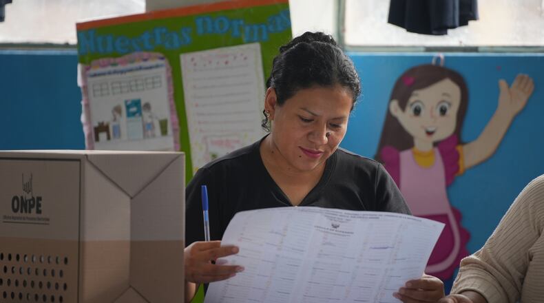 An election official checks voter lists as voting resumes at polling stations affected by delays and logistical problems during general elections in Lima, Peru, Monday, April 13, 2026. (AP Photo/Guadalupe Pardo)