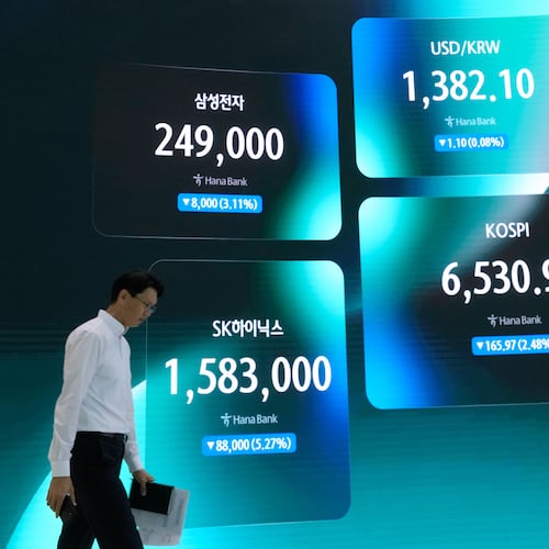 A currency trader passes by a screen showing the Korea Composite Stock Price Index (KOSPI), the foreign exchange rate between U.S. dollar and South Korean won, SK Hynix and Samsung Electronics Co. stock price at the foreign exchange dealing room of the Hana Bank headquarters in Seoul, South Korea, Tuesday, Aug. 25, 2026. (AP Photo/Ahn Young-joon)