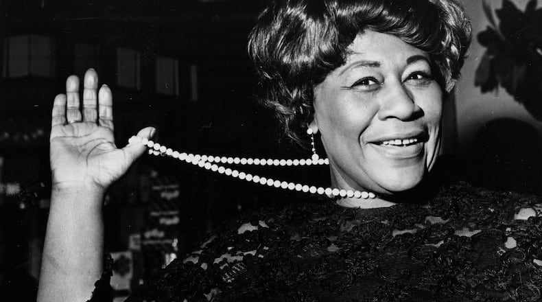 In this Feb. 22, 1968 file photo, American jazz singer Ella Fitzgerald swings her necklace as she arrives at the Carlton Theatre in London, England. The National Portrait Gallery is putting up a photograph of Fitzgerald, often referred to as "The First Lady of Song." The portrait is on view beginning Thursday, April 13, 2017, ahead of the 100th anniversary of Fitzgerald's birth. Fitzgerald, who died in 1996 at the age of 79, would have celebrated her 100th birthday April 25. (AP Photo/Bob Dear, File)