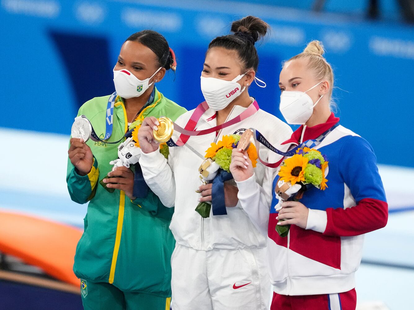 Gold medal winner Sunisa Lee of the United States, is flanked by silver medalist Rebeca Andrade of Brazil, left, and bronze medalist Angelina Melnikova of the Russian Olympic Committee during the medal ceremony for.the women's all-around gymnastics competition at the postponed 2020 Tokyo Olympics in Tokyo on Thursday, July 29, 2021. (Chang W. Lee/The New York Times)