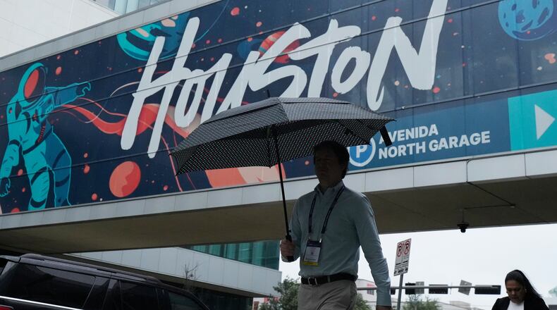 A convention attendee walk through the rain outside the George R. Brown Convention Center, Wednesday, June 17, 2026, in Houston. (AP Photo/Kevin M. Cox)