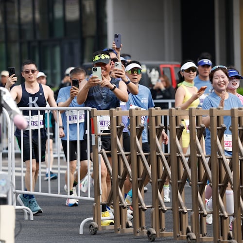 Runners take pictures of a humanoid robot in the second Beijing E-Town Half Marathon and Humanoid Robot Half Marathon in Beijing Sunday, April 19, 2026. (Haruna Furuhashi/Pool Photo via AP)