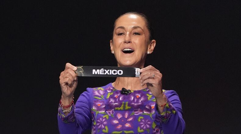 Mexican President Claudia Sheinbaum holds up the team name of Mexico during the draw for the 2026 soccer World Cup at the Kennedy Center in Washington, Friday, Dec. 5, 2025.(AP Photo/Evan Vucci)