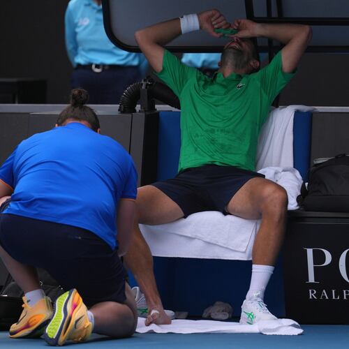 Novak Djokovic of Serbia reacts as he receives treatment to a foot injury during his quarterfinal match against Lorenzo Musetti of Italy at the Australian Open tennis championship in Melbourne, Australia, Wednesday, Jan. 28, 2026. (AP Photo/Dita Alangkara)