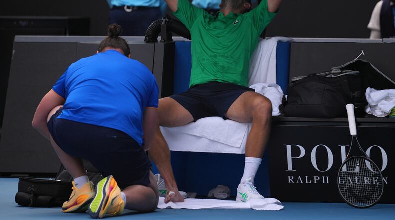 Novak Djokovic of Serbia reacts as he receives treatment to a foot injury during his quarterfinal match against Lorenzo Musetti of Italy at the Australian Open tennis championship in Melbourne, Australia, Wednesday, Jan. 28, 2026. (AP Photo/Dita Alangkara)