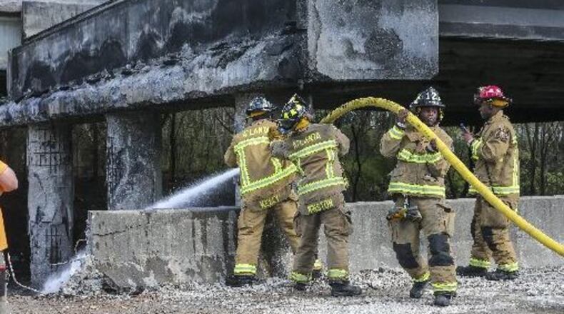 Atlanta firefighters remained on the scene putting out a smoldering fire Friday, March 31, 2017 at the I-85 collapse site while construction crews made their way into the zone to begin work. Officials are planning long-term closures and indefinite repairs. JOHN SPINK /JSPINK@AJC.COM
