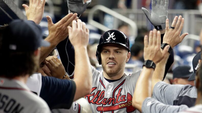Atlanta Braves' Freddie Freeman is congratulated in the dugout after hitting a solo home run during the first inning of the team's baseball game against the Miami Marlins, Friday, May 3, 2019, in Miami. (AP Photo/Lynne Sladky)