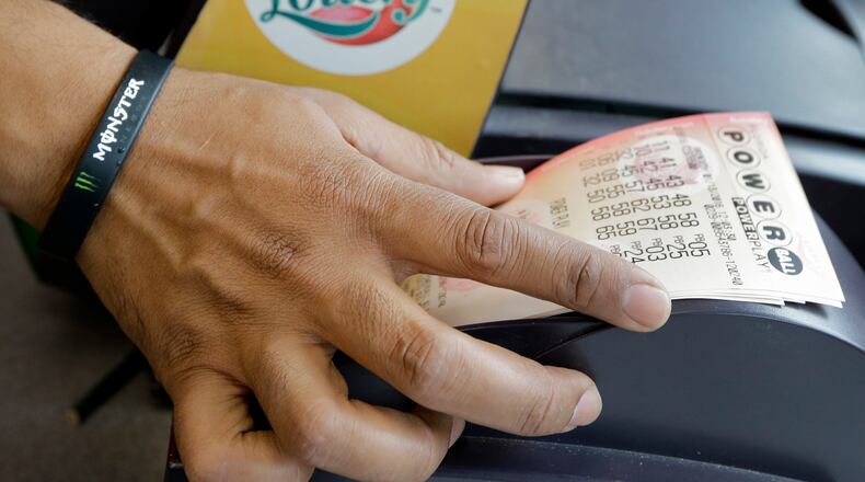 FILE - In this Jan. 13, 2016 file photo, a clerk at a convenience store pulls Powerball tickets from a printer for a customer in Tampa, Fla. The Powerball jackpot for the Wednesday, July 27, 2016, drawing has soared to over $420 million thanks to nearly three months without a winner of the big prize. (AP Photo/Chris O'Meara, File)