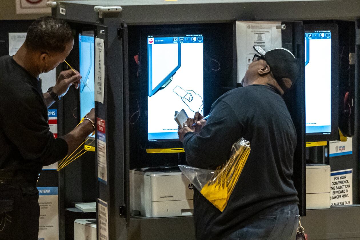 Poll workers Lon Perdue (left) and Ruth Hardy prepare voting machines before the Nov. 5, 2024, election. (John Spink/AJC)