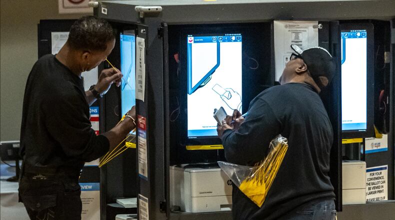Poll workers Lon Perdue (left) and Ruth Hardy prepare voting machines before the Nov. 5, 2024, election. (John Spink/AJC)