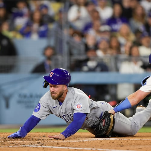 Chicago Cubs' Michael Busch, left, is tagged out by Los Angeles Dodgers catcher Will Smith, right, while attempting to score off a single hit by Alex Bregman during the fourth inning of a baseball game Friday, April 24, 2026, in Los Angeles. (AP Photo/Ryan Sun)