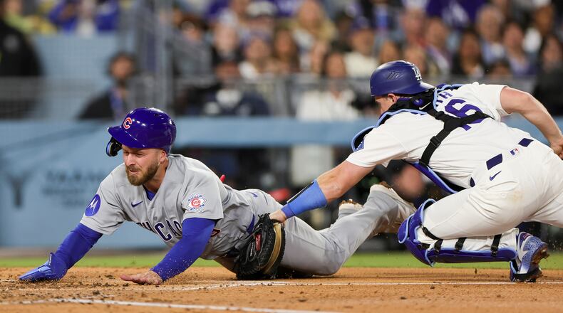 Chicago Cubs' Michael Busch, left, is tagged out by Los Angeles Dodgers catcher Will Smith, right, while attempting to score off a single hit by Alex Bregman during the fourth inning of a baseball game Friday, April 24, 2026, in Los Angeles. (AP Photo/Ryan Sun)