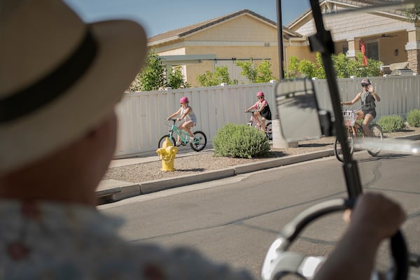 Residents greet Joe Johnston, founder of Agritopia, a community nestled around a plot of agricultural land, as he makes his rounds in his golf cart April 22, 2025, in Gilbert, Ariz. (AP Photo/Annika Hammerschlag)