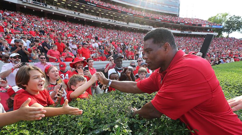 Georgia politicians, including U.S. Senate candidate Herschel Walker, a Republican, rallied behind the state's college football teams over the weekend. Above, Walker greets fans before he is introduced as a member of Georgia's 1980 National Championship team during half time ceremonies against UAB in a NCAA college football game on Sept 11, 2021, in Athens. (Curtis Compton / Curtis.Compton@ajc.com)