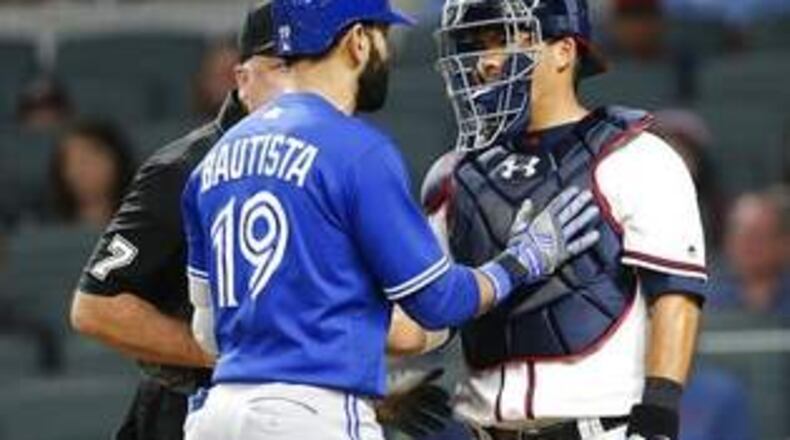 Toronto’s Jose Bautista and Braves catcher Kurt Suzuki exchange words after Bautista’s bat-flip and stare-down of Braves following an eighth-inning home run. (AP photo)