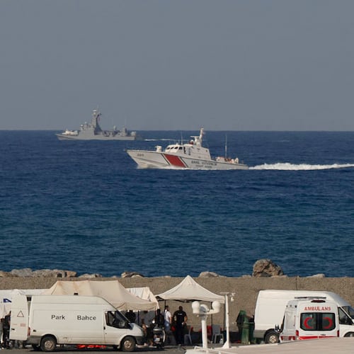Vessels sail near the port of Kyrenia as an ambulance is parked on the waterfront in the Turkish-occupied northern part of Cyprus, Sunday, Aug. 30, 2026, after a catamaran-style ferry overturned off the island's northern coast. (AP Photo/Nedim Enginsoy)