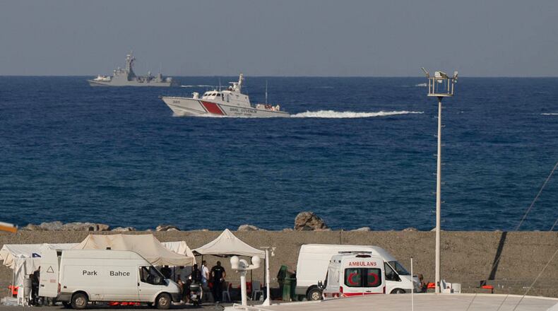 Vessels sail near the port of Kyrenia as an ambulance is parked on the waterfront in the Turkish-occupied northern part of Cyprus, Sunday, Aug. 30, 2026, after a catamaran-style ferry overturned off the island's northern coast. (AP Photo/Nedim Enginsoy)