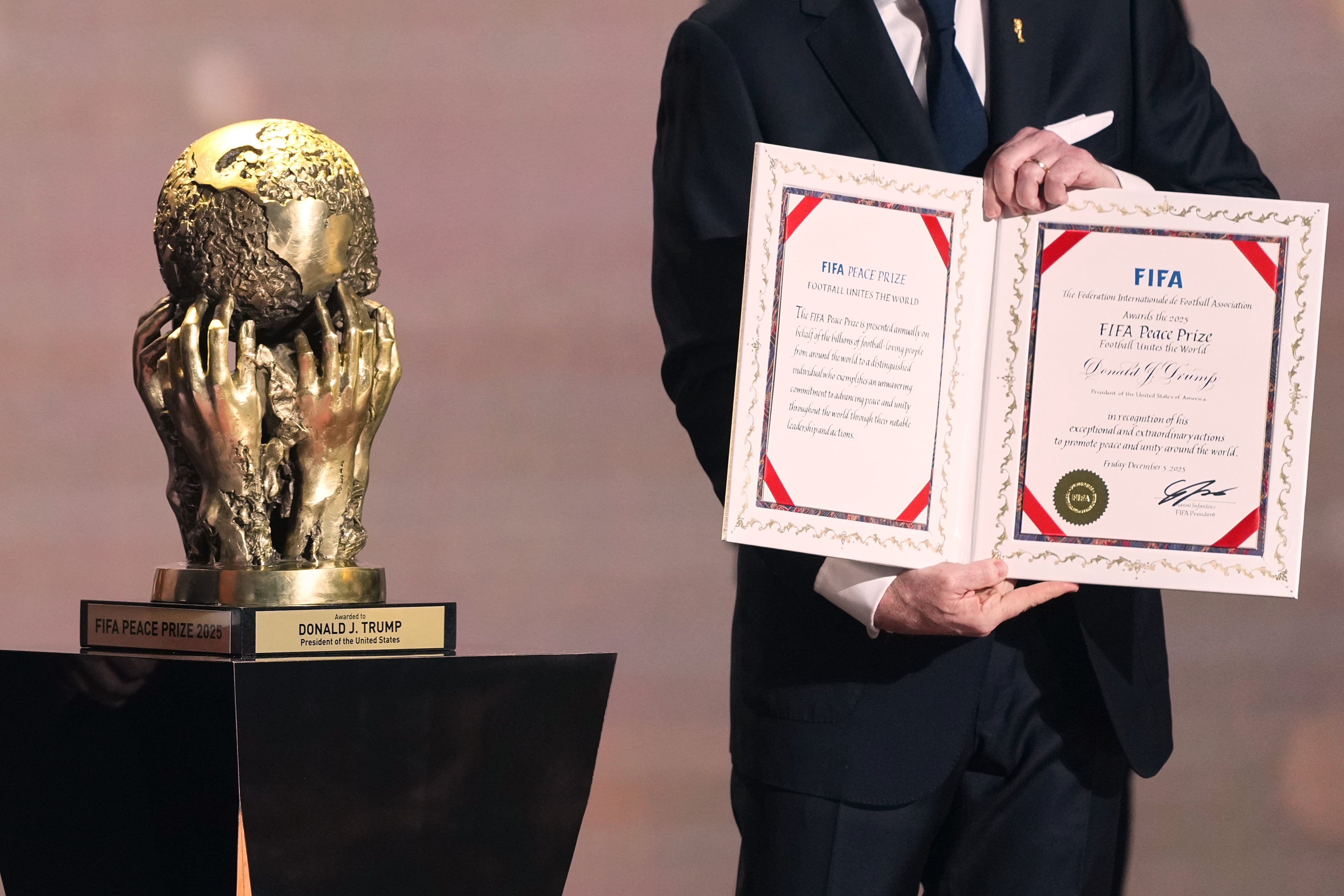 FIFA President Gianni Infantino presents President Donald Trump with the FIFA Peace Prize during the draw for the 2026 soccer World Cup at the Kennedy Center in Washington, Friday, Dec. 5, 2025. (AP Photo/Stephanie Scarbrough, Pool)