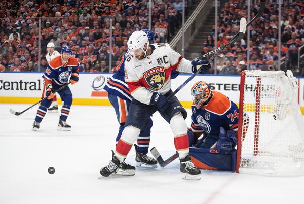 Florida Panthers' Aleksander Barkov (16) and Edmonton Oilers' Evan Bouchard (2) battle in front as goalie Stuart Skinner (74) makes the save during the third period in Game 1 of the NHL hockey Stanley Cup final series in Edmonton, Alberta, Wednesday, June 4, 2025. (Jason Franson/The Canadian Press via AP)