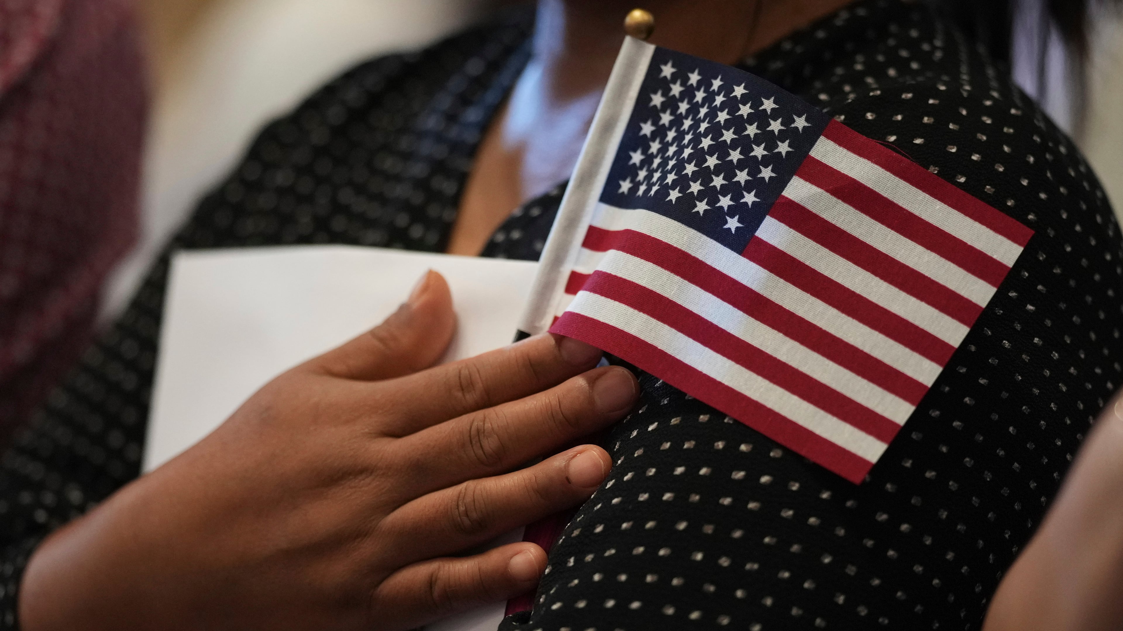 FILE - A woman clutches a U.S. flag as she and applicants from other countries prepare to take the oath of citizenship in commemoration of Independence Day during a Naturalization Ceremony in San Antonio, July 3, 2025. (AP Photo/Eric Gay, File)