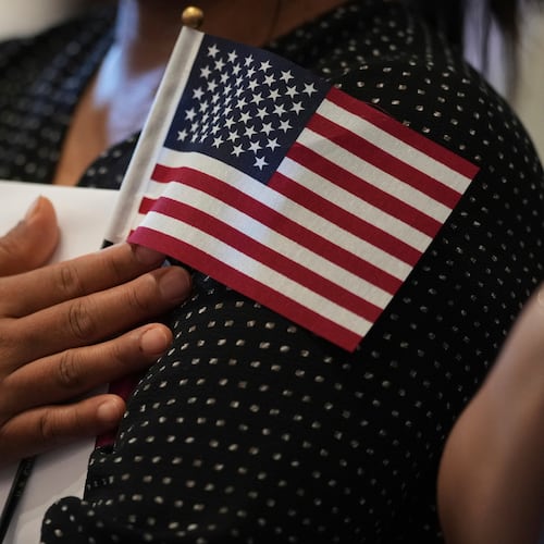 FILE - A woman clutches a U.S. flag as she and applicants from other countries prepare to take the oath of citizenship in commemoration of Independence Day during a Naturalization Ceremony in San Antonio, July 3, 2025. (AP Photo/Eric Gay, File)