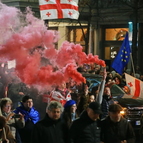Demonstrators with Georgian and EU flags light flares as they gather in the Georgian capital of Tbilisi, on Friday, Nov. 28, 2025, to mark 365 days of non-stop protests against the government's decision to halt talks on joining the European Union. (AP Photo/Zurab Tsertsvadze)
