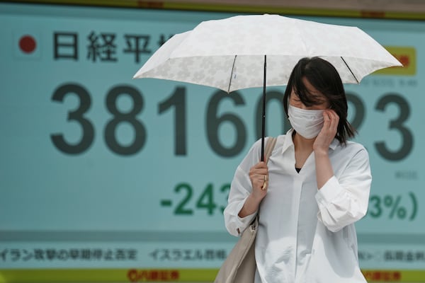 A person walks in front of an electronic stock board showing Japan's Nikkei index at a securities firm Monday, June 23, 2025, in Tokyo. (AP Photo/Eugene Hoshiko)