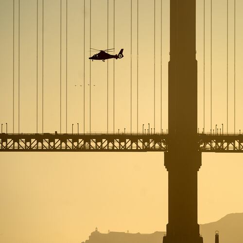 A helicopter flies past the Golden Gate Bridge while searching for missing victims after a boat accident near Alcatraz Island off San Francisco, Tuesday, July 14, 2026. (AP Photo/Noah Berger)