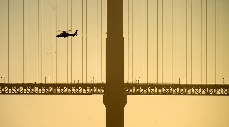 A helicopter flies past the Golden Gate Bridge while searching for missing victims after a boat accident near Alcatraz Island off San Francisco, Tuesday, July 14, 2026. (AP Photo/Noah Berger)