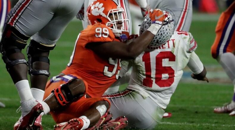 Clemson defensive end Clelin Ferrell (99) grabs Ohio State quarterback J.T. Barrett (16) after the throw during the second half of the Fiesta Bowl NCAA college football game, Saturday, Dec. 31, 2016, in Glendale, Ariz. (AP Photo/Rick Scuteri)